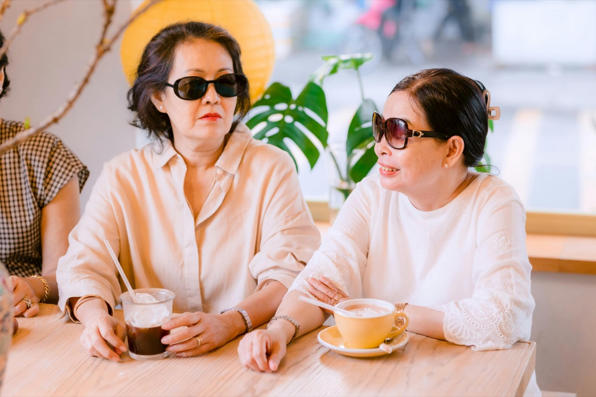 Two women sitting together in a cafe and talking over coffee.