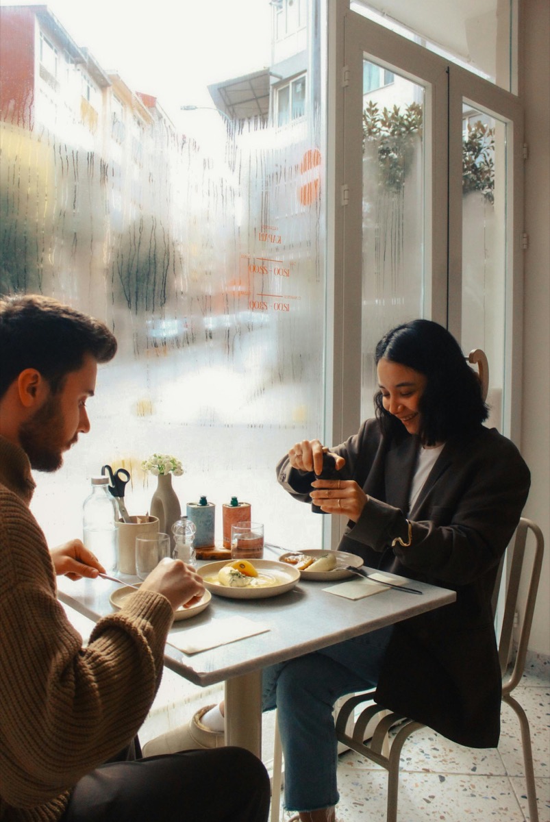Two people sharing a quiet meal by a bright cafe window.